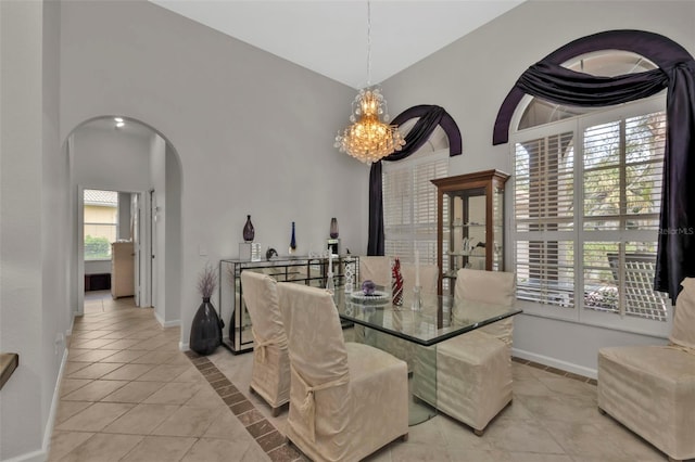 tiled dining area featuring a notable chandelier and high vaulted ceiling