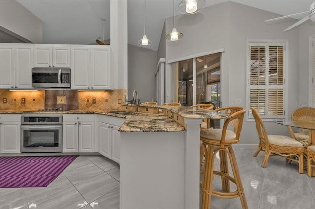 kitchen featuring white cabinets, hanging light fixtures, sink, appliances with stainless steel finishes, and kitchen peninsula