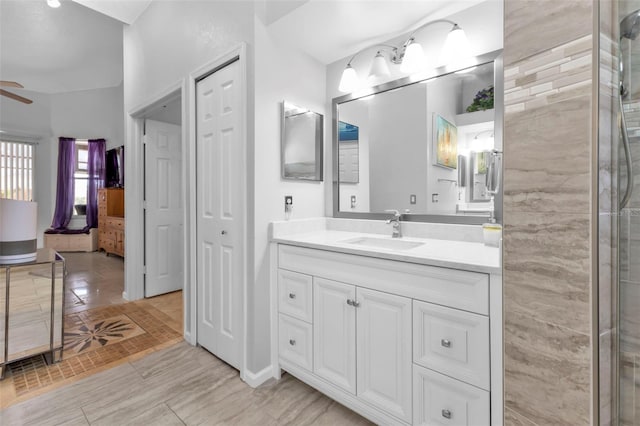 bathroom with a tile shower, vanity, vaulted ceiling, and ceiling fan