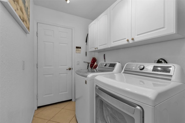 laundry room featuring cabinets, independent washer and dryer, and light tile patterned floors