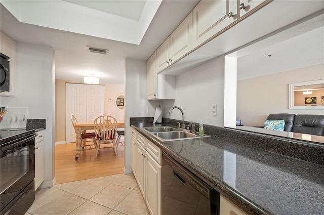 kitchen featuring light tile patterned floors, sink, dark stone countertops, and black appliances