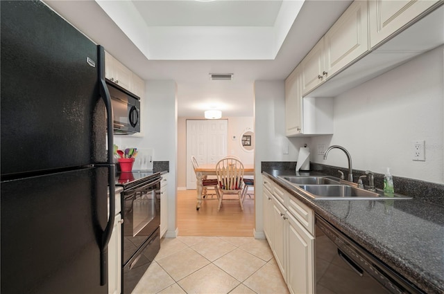 kitchen featuring black appliances, sink, a tray ceiling, light tile patterned flooring, and white cabinetry