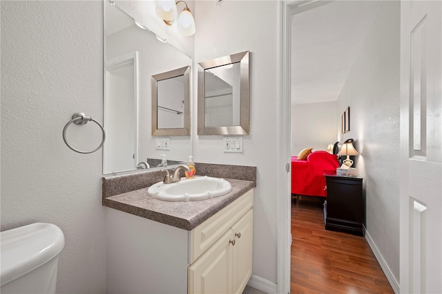 bathroom with hardwood / wood-style flooring, vanity, and toilet