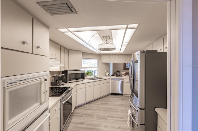 kitchen featuring light wood-type flooring, stainless steel appliances, white cabinetry, and sink