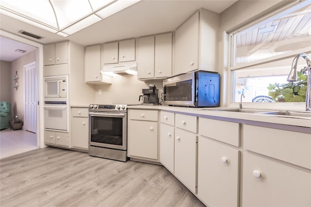 kitchen featuring white appliances, sink, light hardwood / wood-style floors, white cabinetry, and lofted ceiling