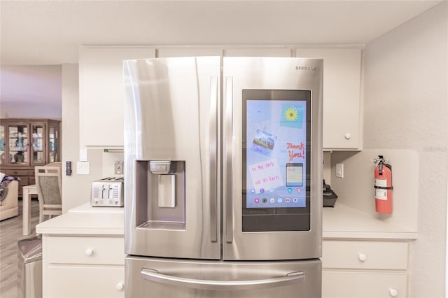 kitchen featuring white cabinets and stainless steel fridge