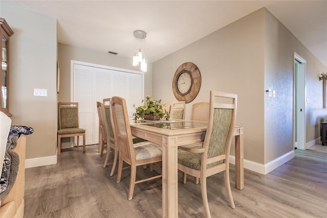 dining space featuring hardwood / wood-style flooring and an inviting chandelier