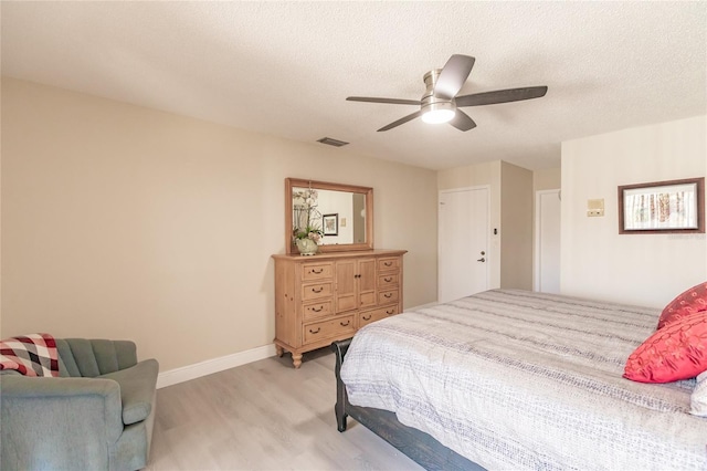 bedroom with ceiling fan, light hardwood / wood-style floors, and a textured ceiling