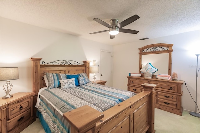 bedroom featuring ceiling fan, light carpet, and a textured ceiling