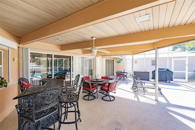 sunroom / solarium with beam ceiling and ceiling fan