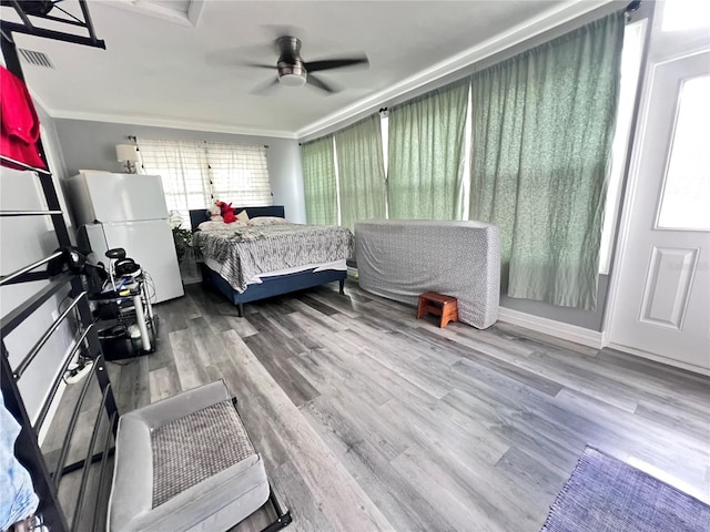 bedroom with ceiling fan, white fridge, wood-type flooring, and ornamental molding