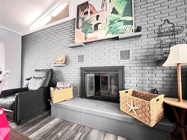 living room with a tile fireplace, wood-type flooring, lofted ceiling, and brick wall