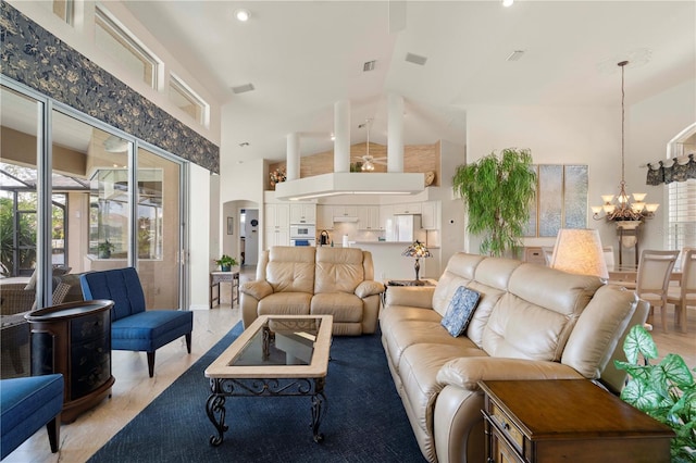 living room with light hardwood / wood-style floors, a high ceiling, and an inviting chandelier