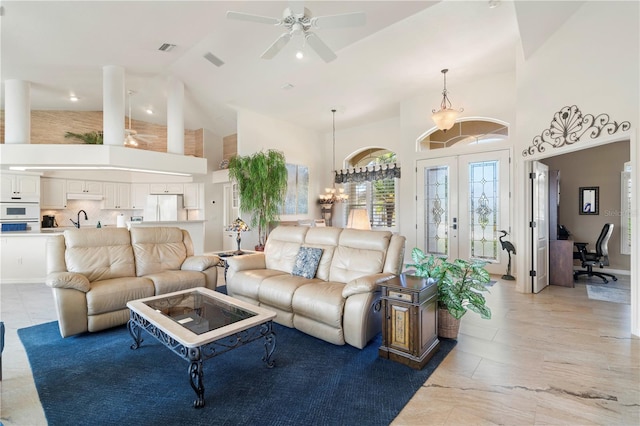 living room featuring french doors, ceiling fan with notable chandelier, high vaulted ceiling, and sink