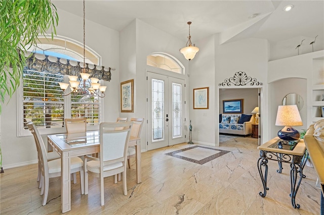 foyer entrance featuring french doors, a towering ceiling, and a chandelier