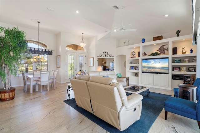 living room with ceiling fan with notable chandelier and high vaulted ceiling