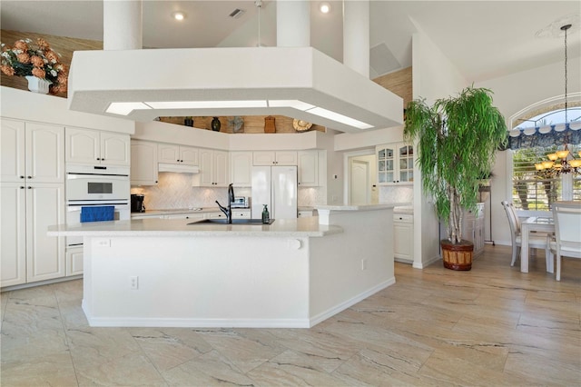 kitchen with white cabinets, high vaulted ceiling, an island with sink, and island exhaust hood