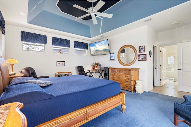 bedroom featuring connected bathroom, a tray ceiling, ceiling fan, and carpet floors