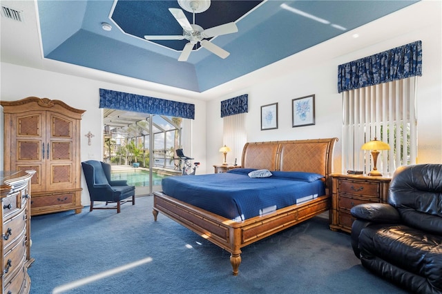 bedroom featuring a tray ceiling, ceiling fan, dark carpet, and access to outside