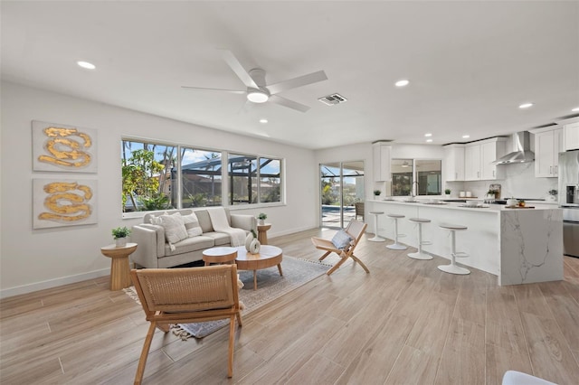 living room with ceiling fan and light hardwood / wood-style flooring