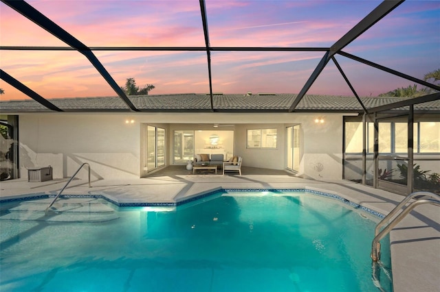 pool at dusk featuring outdoor lounge area, a patio area, and a lanai