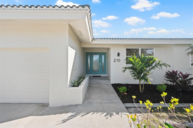 property entrance featuring a garage and french doors