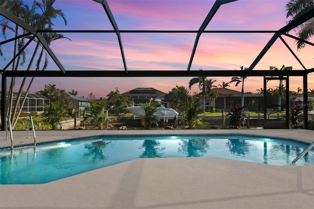 pool at dusk with a lanai and a patio