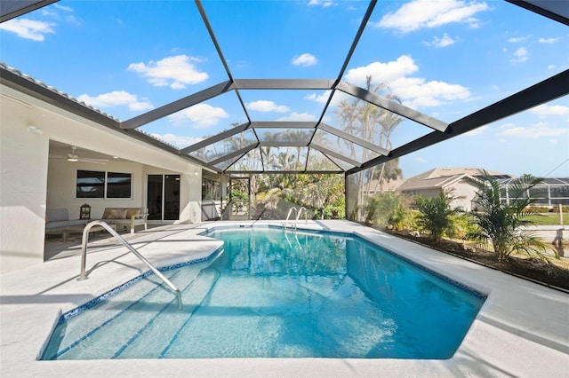 view of pool with a patio, glass enclosure, and ceiling fan