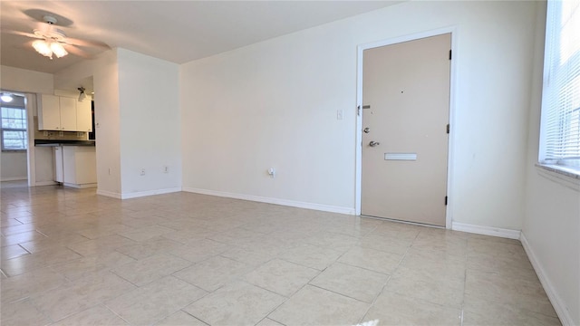 spare room with ceiling fan, a healthy amount of sunlight, and light tile patterned flooring