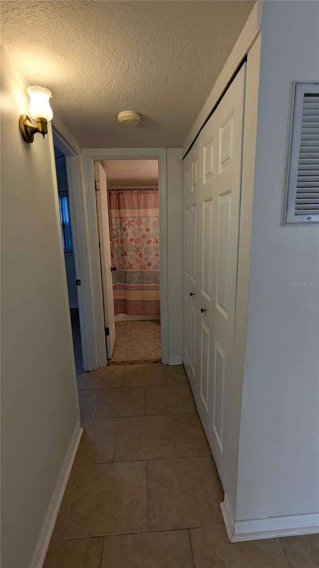 corridor featuring tile patterned floors and a textured ceiling