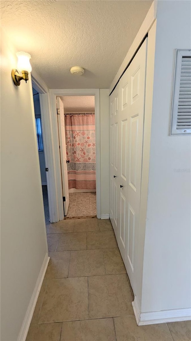 hallway with light tile patterned floors and a textured ceiling