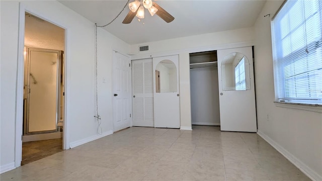 unfurnished bedroom featuring ceiling fan and two closets