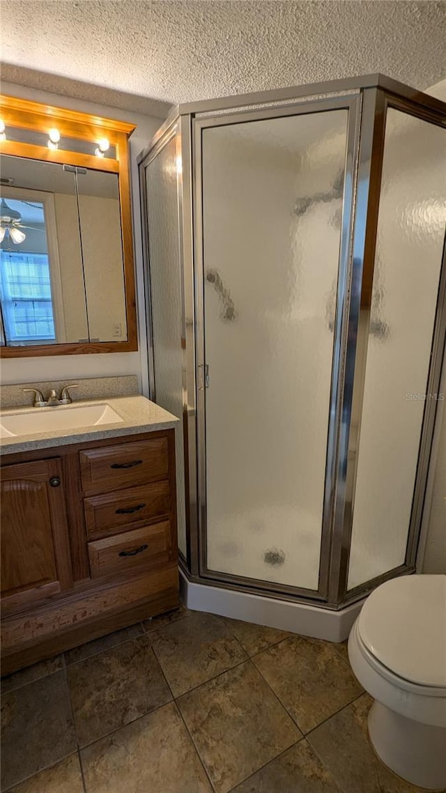 bathroom with tile patterned flooring, a shower with shower door, and a textured ceiling