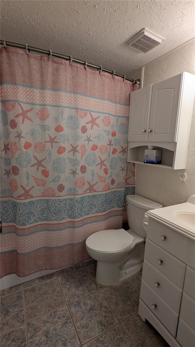 bathroom with vanity, tile patterned floors, toilet, a textured ceiling, and walk in shower