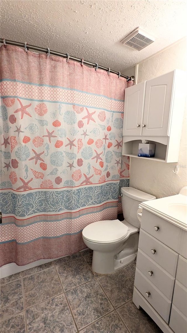 bathroom featuring tile patterned flooring, vanity, toilet, and a textured ceiling