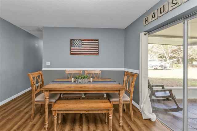 dining room with wood-type flooring and a textured ceiling