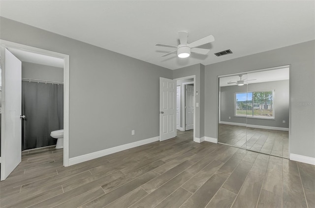 unfurnished bedroom featuring ceiling fan, ensuite bathroom, and a closet