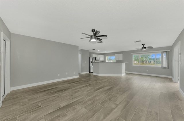 unfurnished living room featuring ceiling fan and light hardwood / wood-style flooring