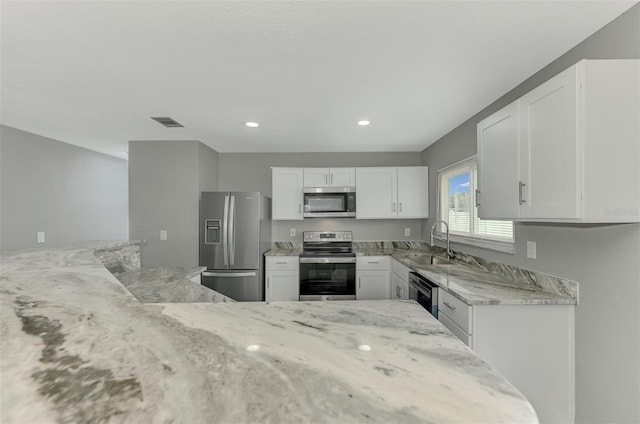 kitchen with light stone countertops, sink, white cabinets, and appliances with stainless steel finishes