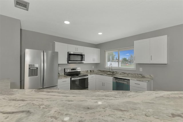 kitchen featuring white cabinets, light stone countertops, sink, and appliances with stainless steel finishes