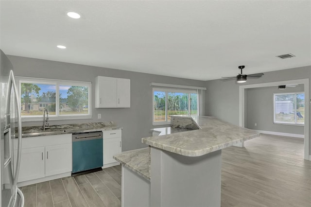 kitchen with a center island, white cabinets, ceiling fan, appliances with stainless steel finishes, and light hardwood / wood-style floors