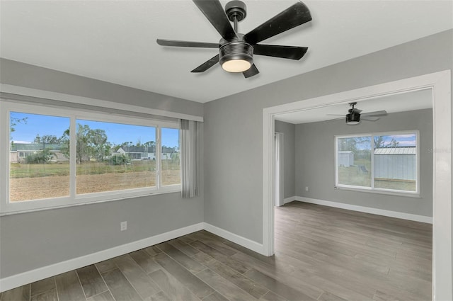 empty room featuring ceiling fan, plenty of natural light, and hardwood / wood-style flooring