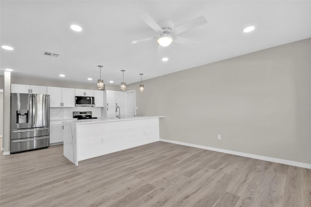 kitchen featuring pendant lighting, stainless steel appliances, white cabinetry, and light hardwood / wood-style floors