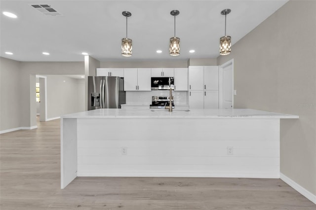 kitchen with white cabinetry, light hardwood / wood-style flooring, decorative light fixtures, and appliances with stainless steel finishes