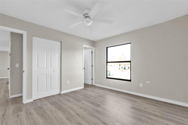 unfurnished bedroom with ceiling fan, light wood-type flooring, and a closet