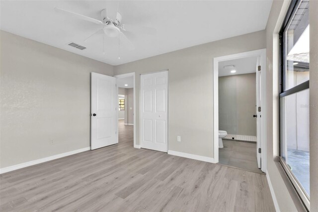 unfurnished bedroom with ceiling fan, light wood-type flooring, and connected bathroom