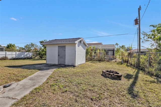 view of outbuilding with a fire pit and a lawn