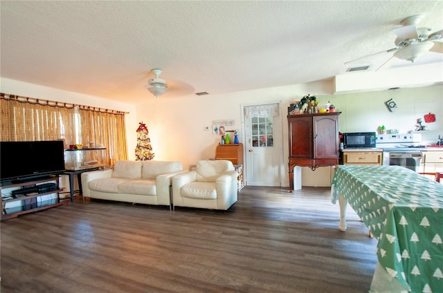 living room featuring ceiling fan, dark hardwood / wood-style flooring, and a textured ceiling