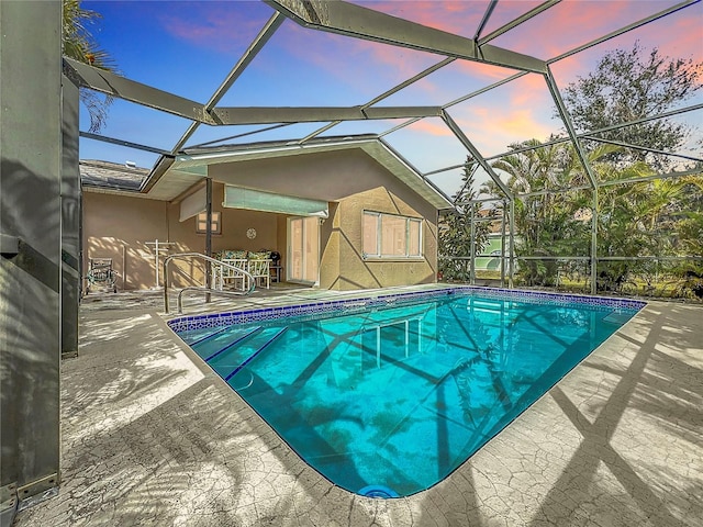 pool at dusk with a patio area and glass enclosure