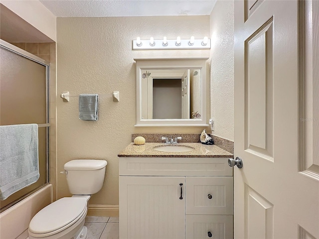 full bathroom with tile patterned floors, vanity, bath / shower combo with glass door, and toilet